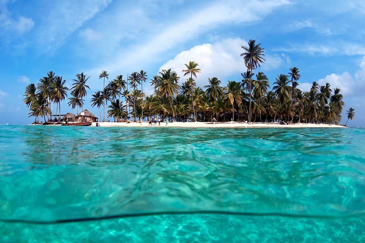 Palm-covered island beyond clear turquoise water in San Blas