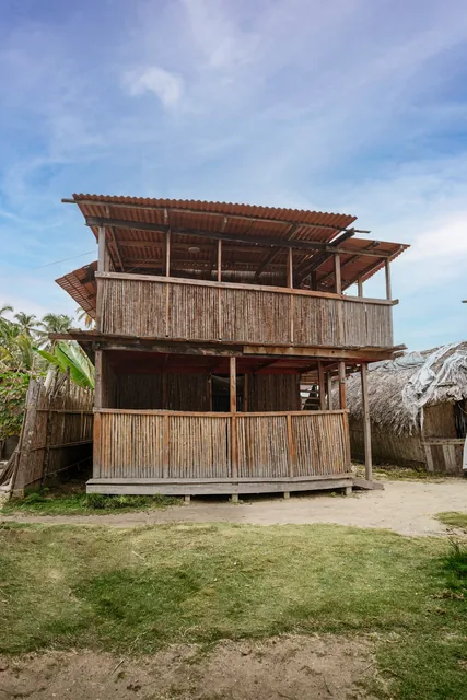 Two-story wooden cabin with covered verandas and reed railings on Naranjo Chico Island in San Blas, Panama.