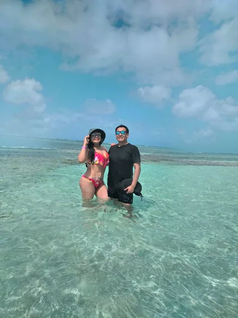 Two guests standing in clear turquoise shallows during a San Blas island-hopping tour in Panama.